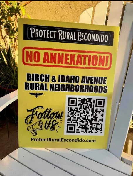 A yellow Protect Rural Escondido yard sign reading No Annexation, Birch & Idaho Avenue Rural Neighborhoods, with a QR code linking to the campaign website.
